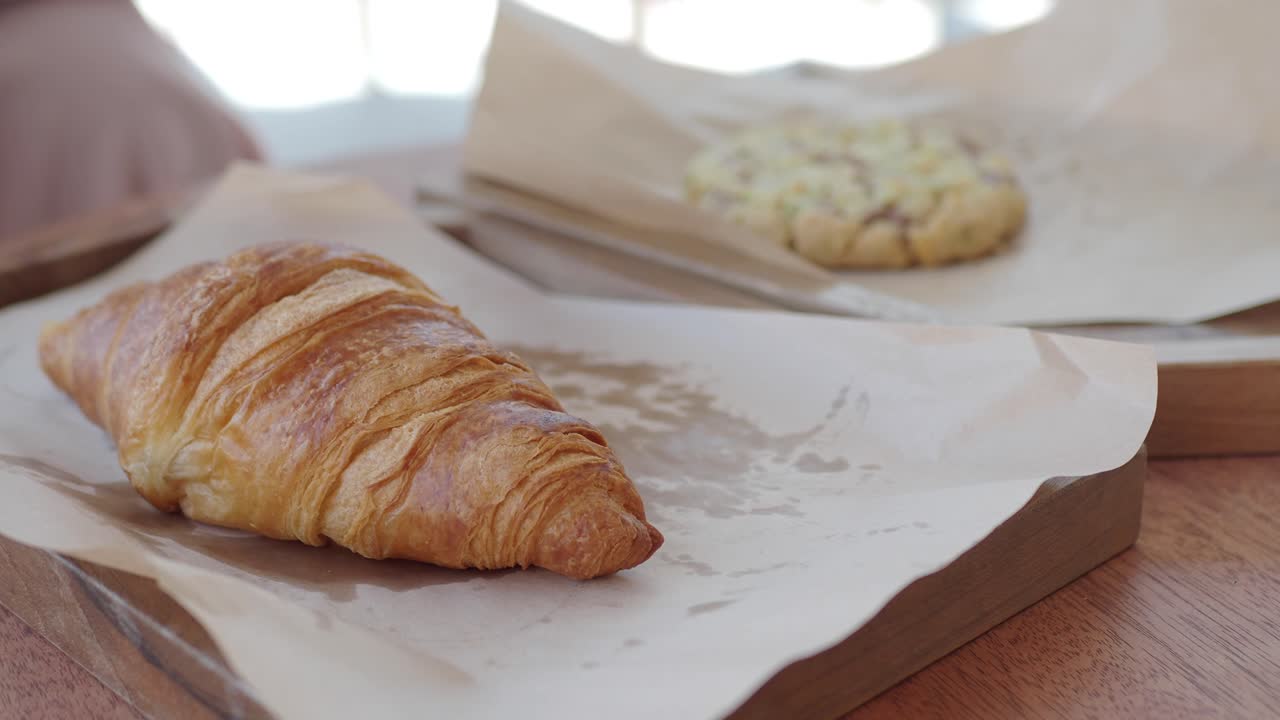 Croissant and cookie on a wooden tray
