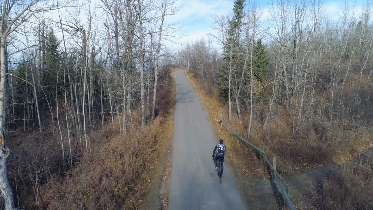 Cycliste roulant sur une route de campagne en forêt 4K