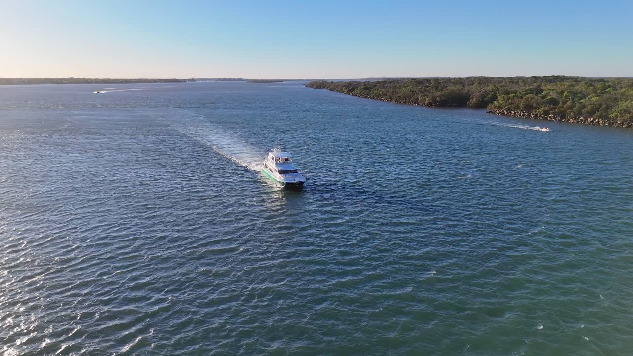 A luxury yacht navigates through the Gold Coast's clear waters under bright sunlight, showcasing serene oceanic beauty