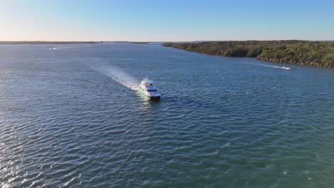 A luxury yacht navigates through the Gold Coast's clear waters under bright sunlight, showcasing serene oceanic beauty