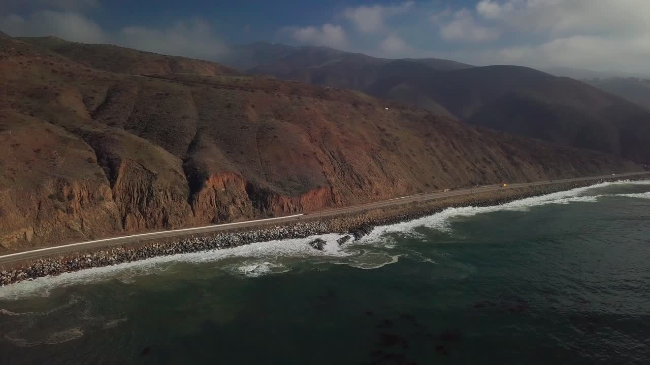 Wide panning shot across the ocean and coastal highway. 4K
