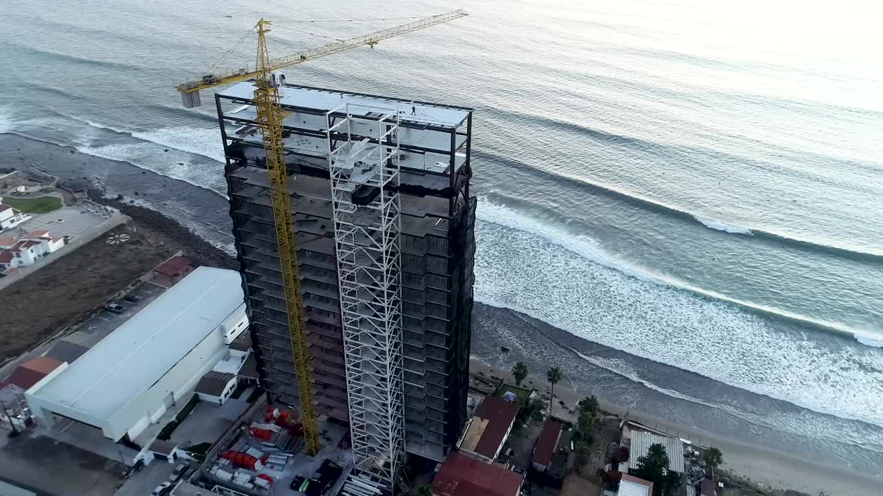 Dron volando sobre un edificio en construcción frente a la costa del mar.