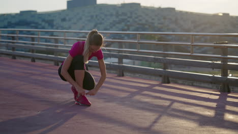 mujer atando cordones de zapatos antes de correr en un puente