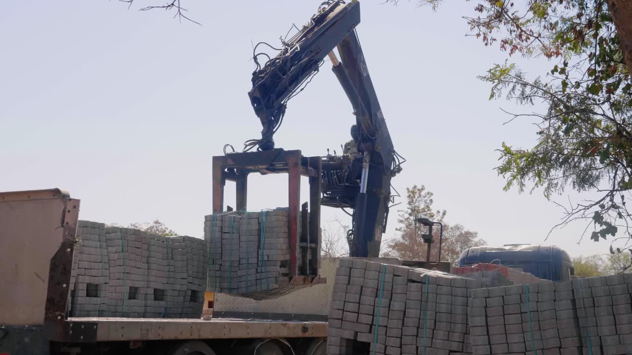African Man unloading bricks from truck using a crane