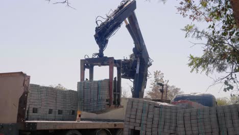 african man unloading bricks from truck using a crane