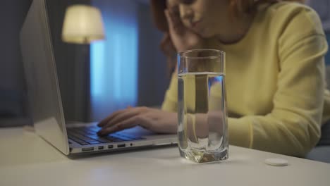 woman taking medicine at night while studying.