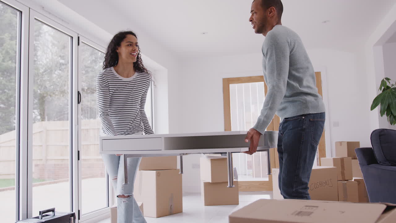 pareja en la nueva casa el día de la mudanza llevando la mesa juntos