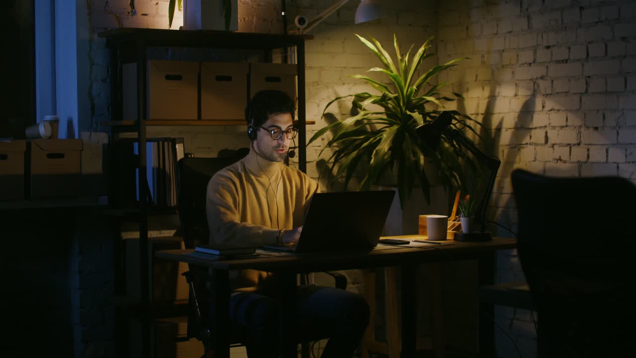 Hombre trabajando hasta tarde por la noche en su oficina en casa