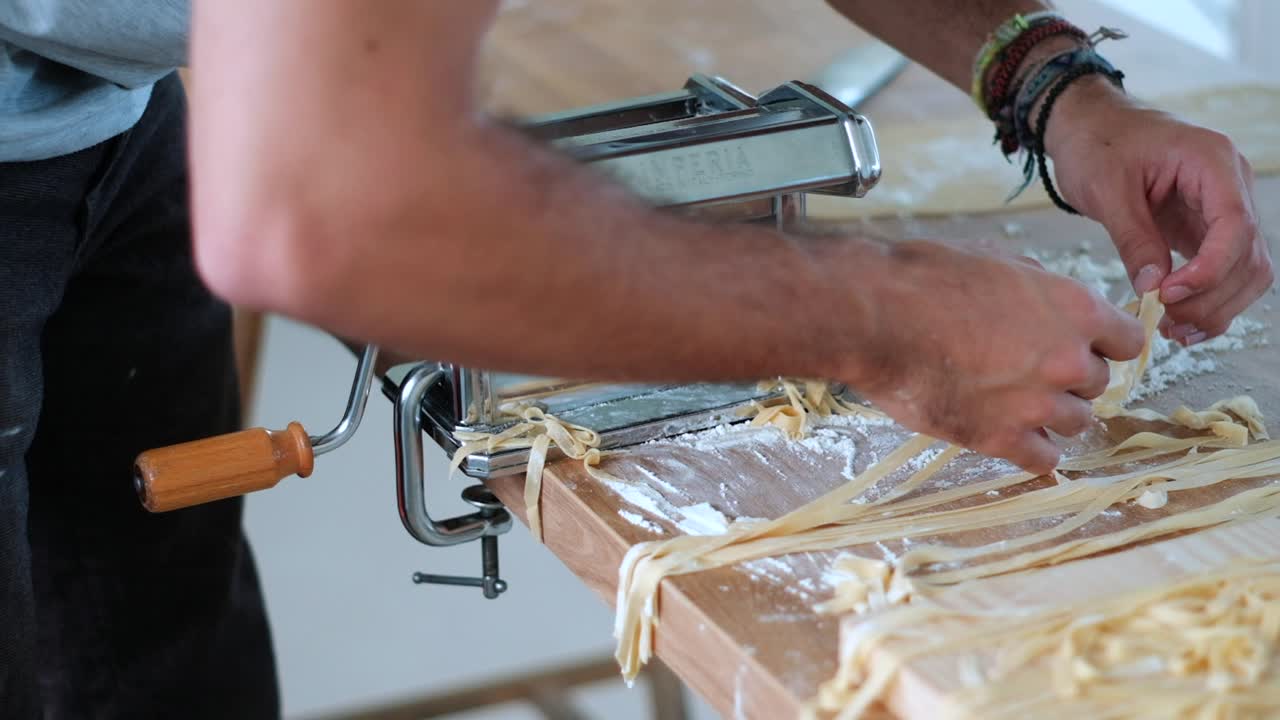 el chef está clasificando la tagliatelle que salió de la máquina de pasta
