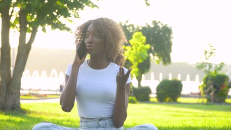 happy african woman talking on the phone in the park on the background of the lake