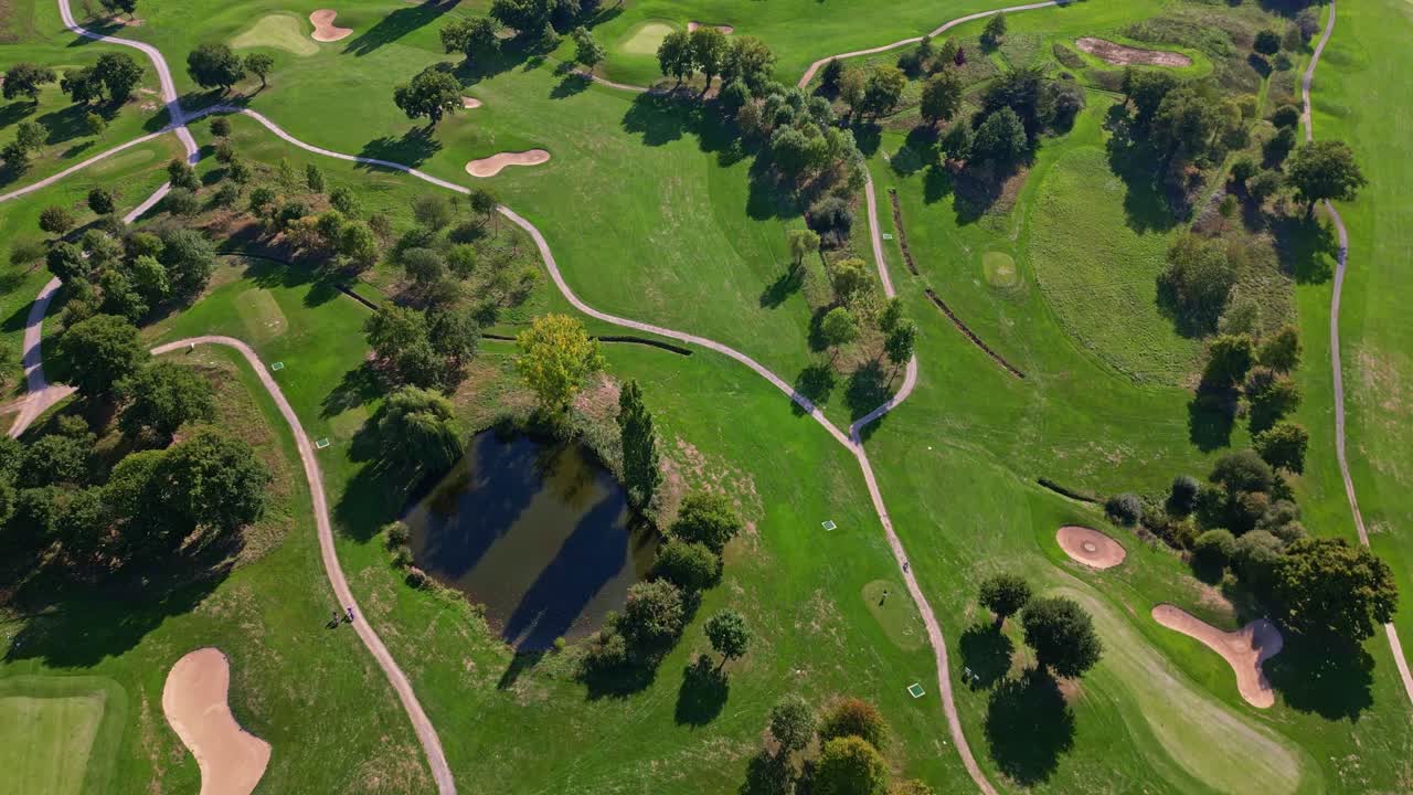 Bird's eye view of golf course showing the graphic patterns of fairways, paths, and ponds. Aerial top-down forward