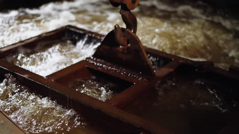 macro shot of crane hook in water with frothy bubbles during metal quenching process