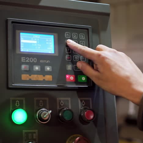 hand pushing the button on factory panel. side view of male hand pushes the control panel buttons during a factory workflow. industry indoors.close-up.
