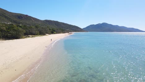 Mujer-Turista-Vagando-Por-La-Orilla-Del-Mar-De-La-Playa-De-La-Bahía-De-Hydeaway-En-El-Norte-De-Queensland,-Australia