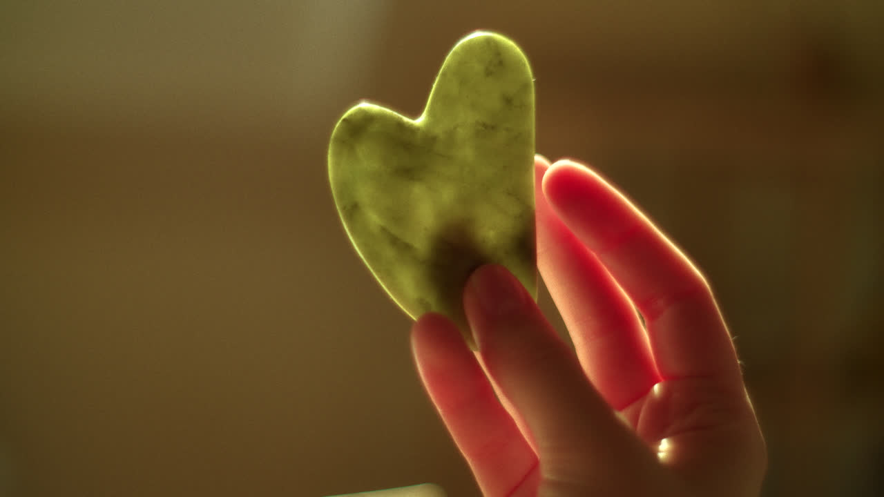 Hand Holding a Heart-Shaped Guasha Tool