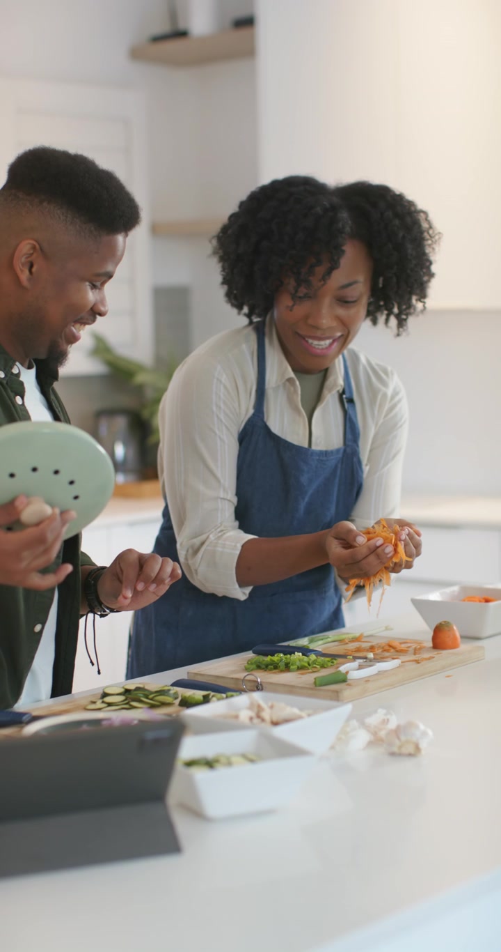Video verticale: Coppia afroamericana che mette le bucce nel contenitore del COMPOST in cucina mentre prepara un pasto.