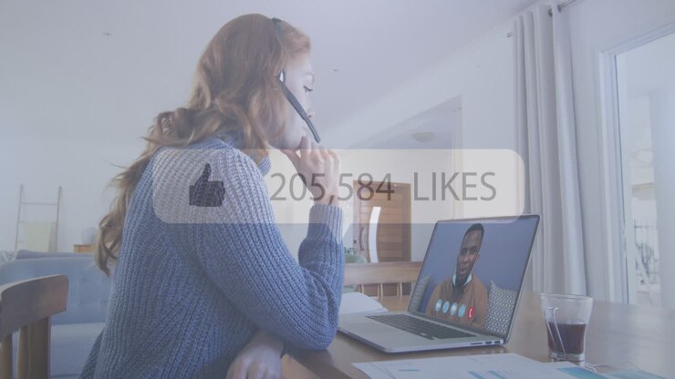 Thumbs up icon and increasing likes against woman having a video call on laptop at office