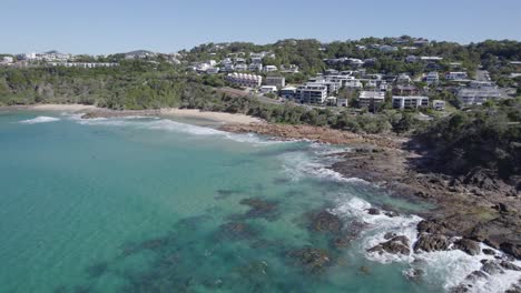 Waves-On-The-Rocky-Shore-With-Coastal-Town-At-The-Bays-Of-Coolum-In-The-Sunshine-Coast-Region,-QLD-Australia