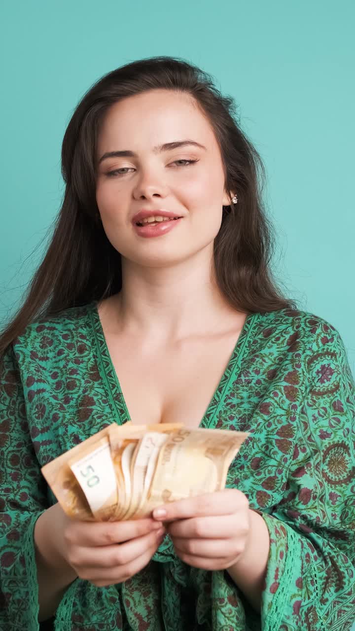 Wanita kaya memamerkan uang kertas euro di studio biru