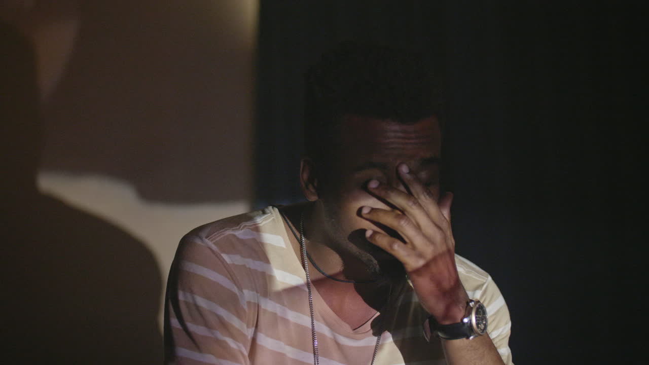 hombre afroamericano viendo películas caseras con frustración