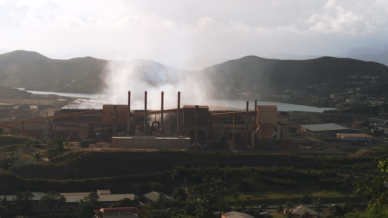 Wide shot of SLN factory in Nouméa, smoking chimneys polluting the air