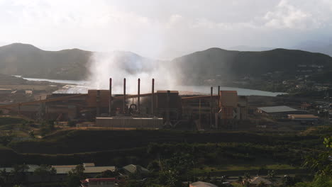 wide shot of sln factory in nouméa, smoking chimneys polluting the air