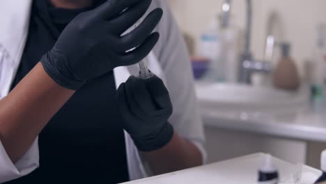 Professional-doctor-in-gloves-and-mask-with-medical-syringe-in-hands,-getting-ready-for-injection.-Close-Up-view