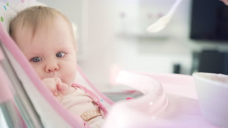 bebé comiendo con cuchara. niño lindo probando papilla. niño pequeño comiendo en silla de bebé