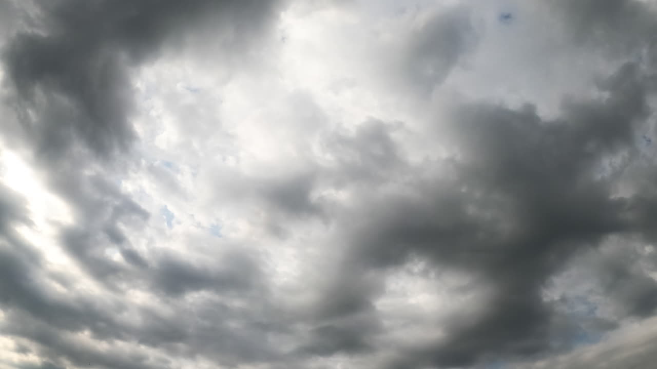 Soft light clouds turn into dark grey cloudscape. Rain formation in the atmosphere. Low angle view. Timelapse.