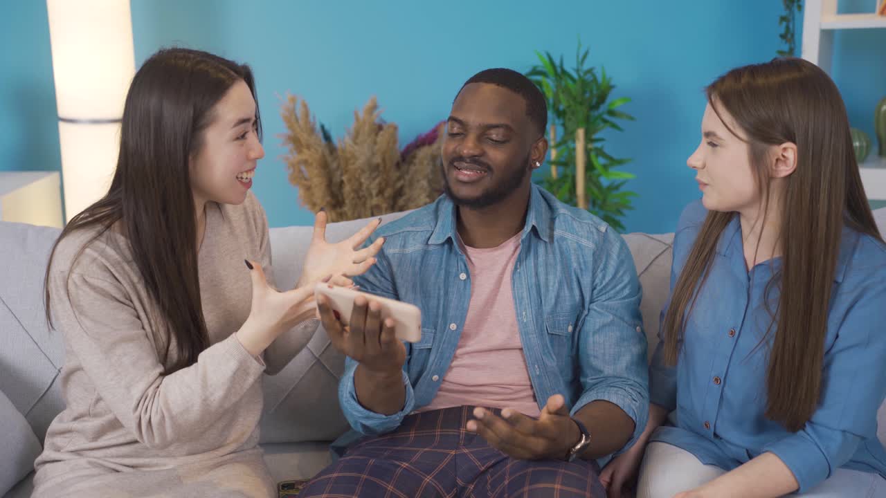 jóvenes de diferentes razas, mirando el teléfono, charlando y riendo.