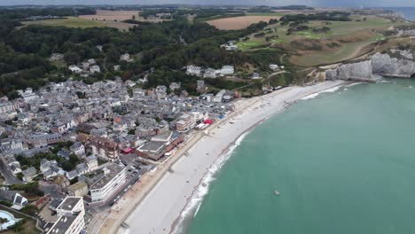 the small village of etretat in normandy in france, filmed with the drone, right on the beach with waves and nice weather