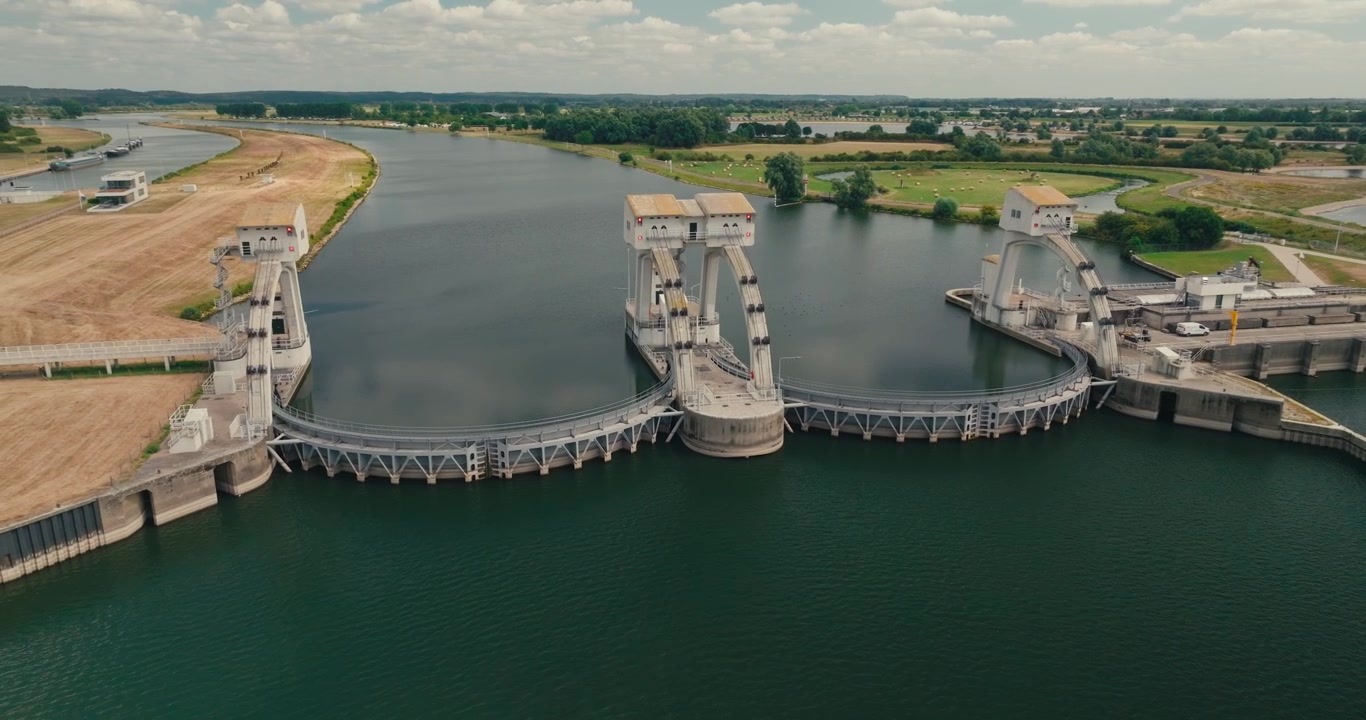 Drone cirkelt rond een dam, sluis en waterkrachtcentrale aan de Nederrijn bij Maurik, waarbij het Nederlandse waterbeheer en de infrastructuur voor hernieuwbare energie worden getoond.