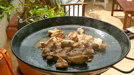 preparing traditional paella in spain - chicken cooking in pan