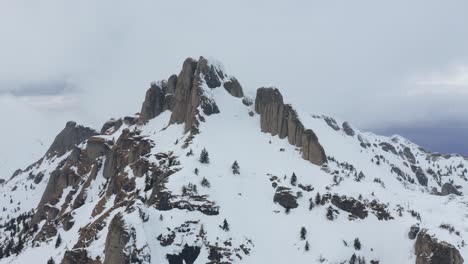 Rugged-Ciucas-Mountains-peak-dusted-with-snow-under-overcast-sky,-winter-landscape