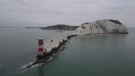 aerial drone flight heading over the red and white lighthouse towards the white cliffs of the needles in the isle of wight