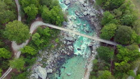 wide aerial shot of untamed mountain river flowing below bridge in spring