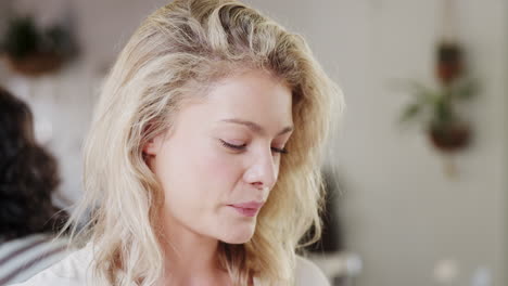 young blonde woman smiling and talking while eating in a restaurant, head and shoulders