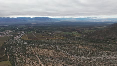 Aerial-drone-shot-of-vineyard-farms-with-Andean-Cordillera-Mountain-Range-in-cafayate-salta-of-Argentina-south-america