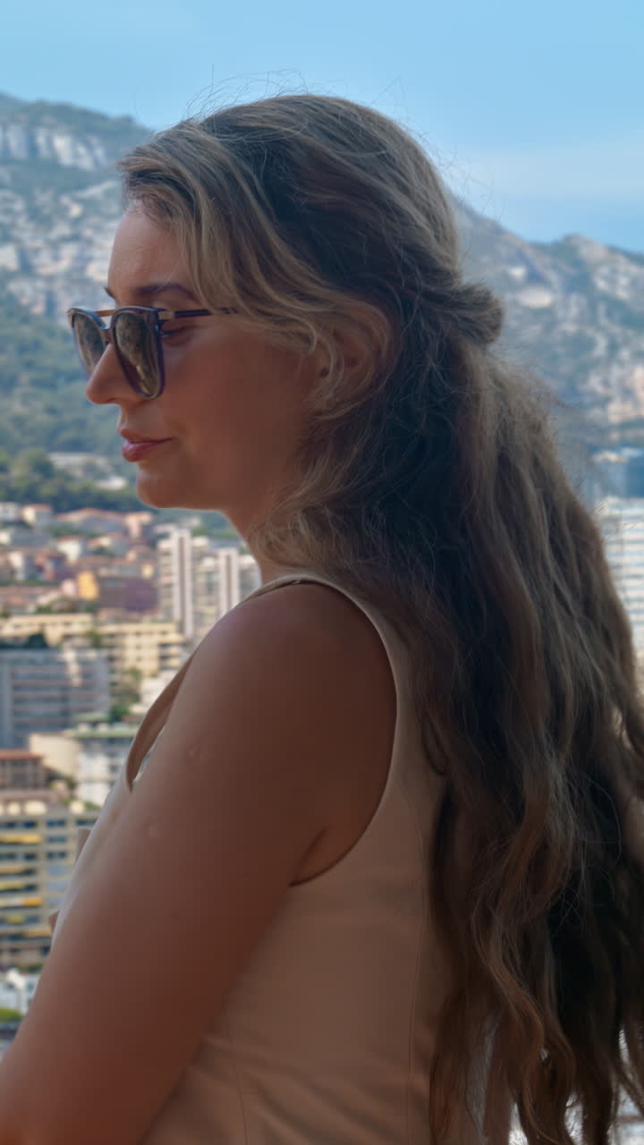 Woman looking at a view of the Monaco Marina with the skyline of the city on the background. Vertical