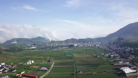 Sobrevuelo-Aéreo-Dieng-Regency-En-Java-Central-Con-Campos-De-Plantaciones-Rurales-Y-Casas-De-Pueblo-Rodeadas-De-Montañas-Durante-El-Día-Soleado-En-Indonesia