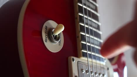 the pick-up switch of a red electric les paul guitar being switched from treble to rhythm