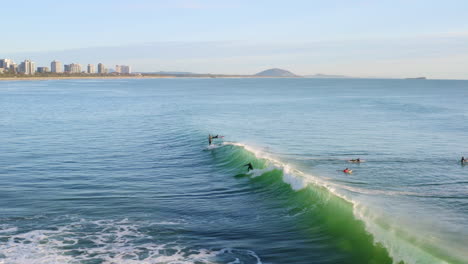 aerial 4k drone tracking surfer catching wave off beach shore in australia