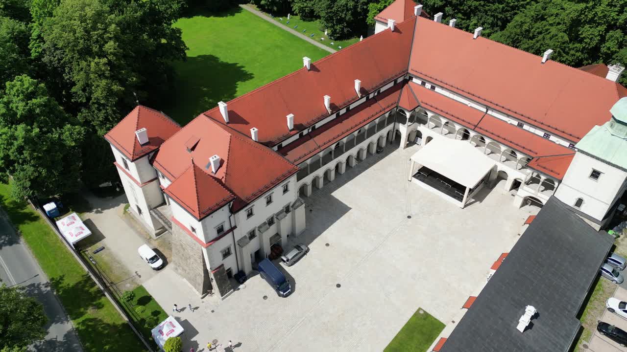 Flight over courtyyard of old castle in Sucha Beskidzka on sunny day - aerial 4K palace