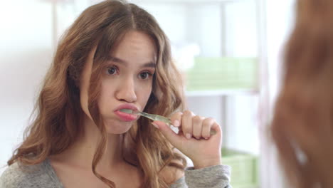 young woman brushing teeth in mirror at home bathroom. girl cleaning teeth