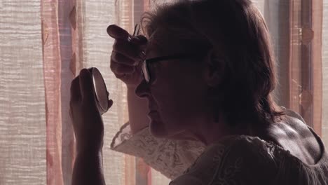 senior woman applying eyebrow makeup
