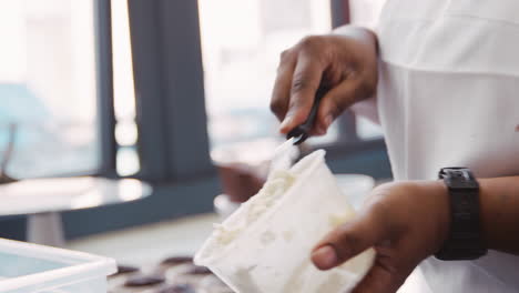 Woman-mixing-cake-frosting-at-a-bakery,-mid-section