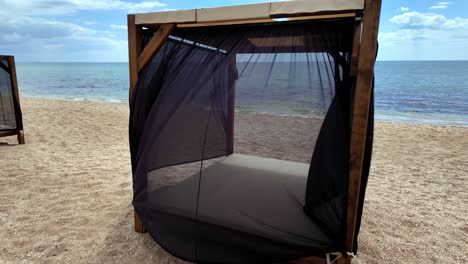 una cabaña de madera con cortinas negras en una playa de arena en crimea