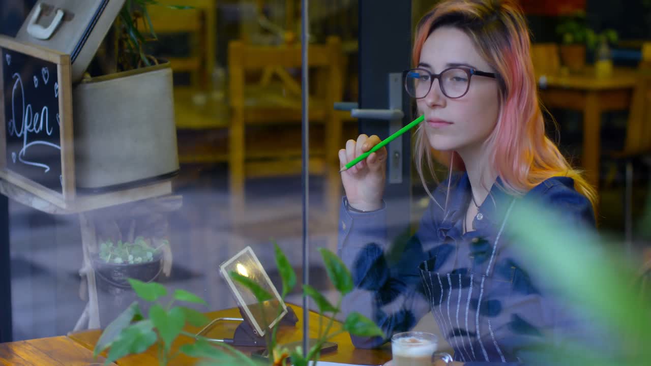 propietaria femenina tomando café frío mientras escribe en un bloc de notas 4k