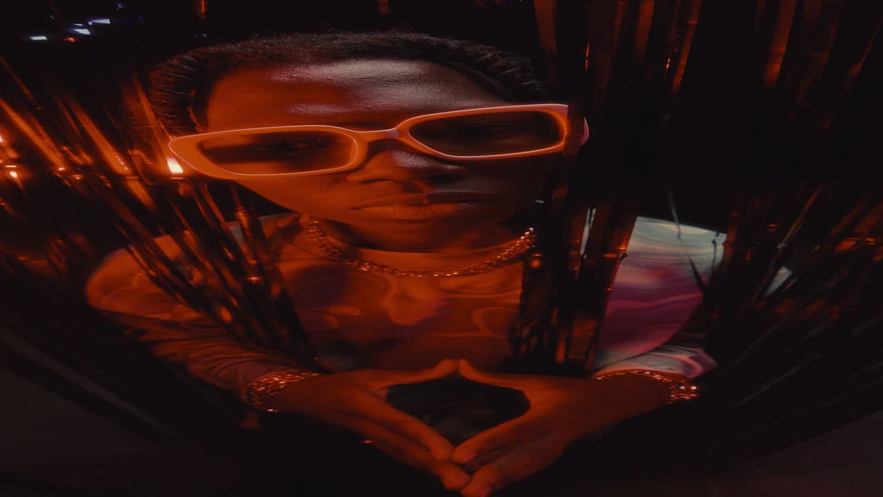 Portrait of Stylish Black Man Posing behind Tinsel Curtain in Nightclub