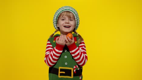 chica linda con disfraz de elfo sosteniendo mandarinas para navidad
